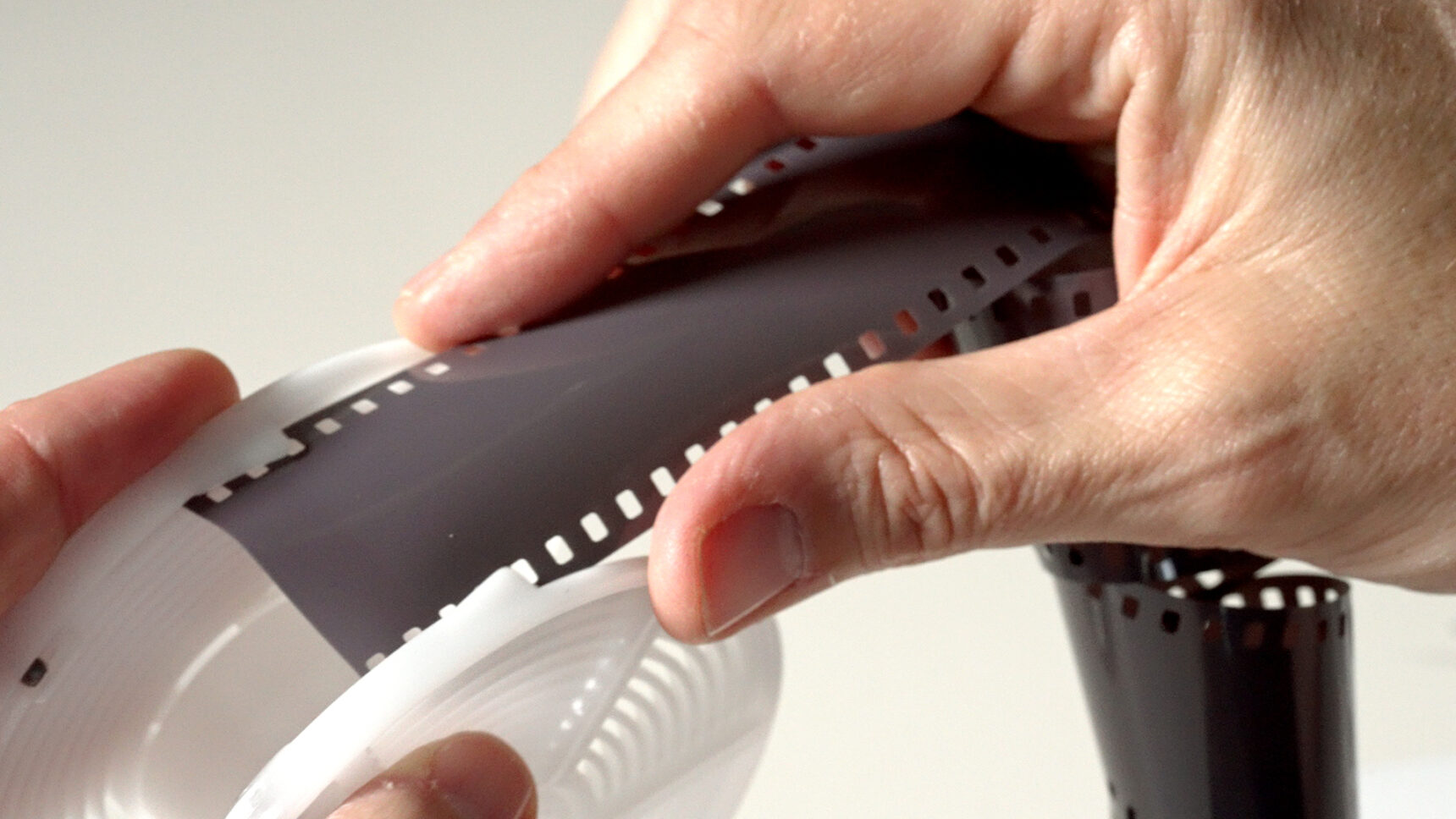 Slide film onto plastic reel.